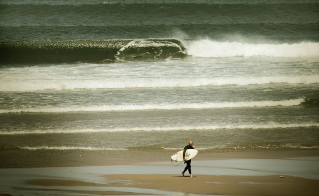  verlässt den Strand mit dem Surfbrett 